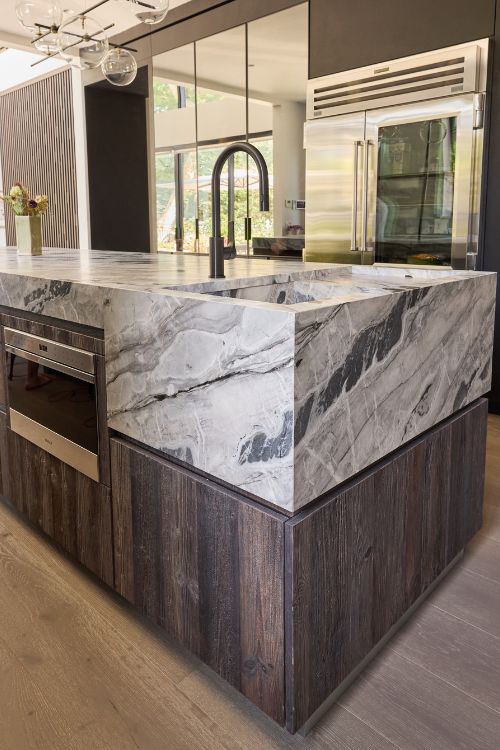 Modern farmhouse kitchen with reclaimed wood island, cement-finish cabinetry, quartzite countertops, and integrated appliances, custom designed by Urban Homes.