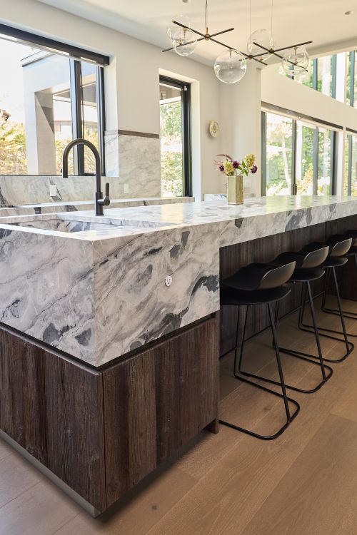 Modern farmhouse kitchen with reclaimed wood island, cement-finish cabinetry, quartzite countertops, and integrated appliances, custom designed by Urban Homes.