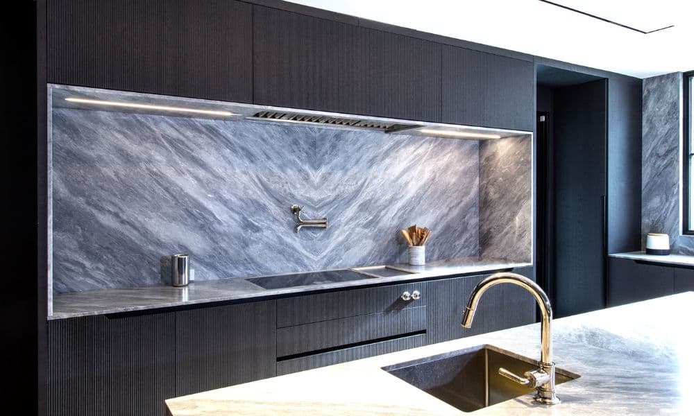 Urban Homes modern kitchen with marble backsplash and sleek dark cabinetry.