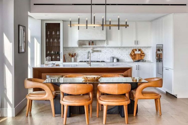 Transitional white kitchen in the Tri-State area with custom cabinetry, waterfall stone island, and brass hardware.